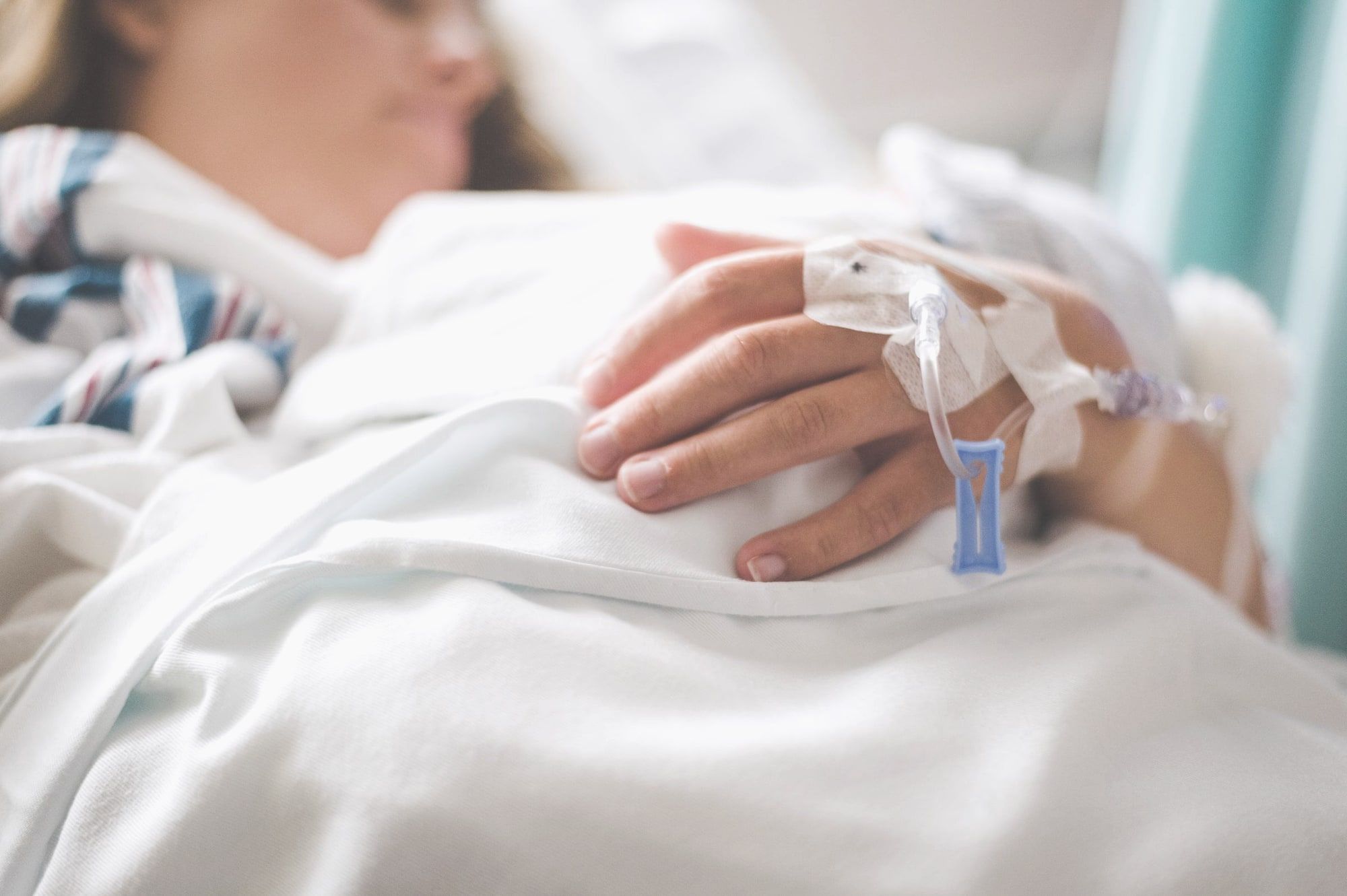 Kanila za infuziju pričvršćena na ruci pacijenta koji leži u krevetu.